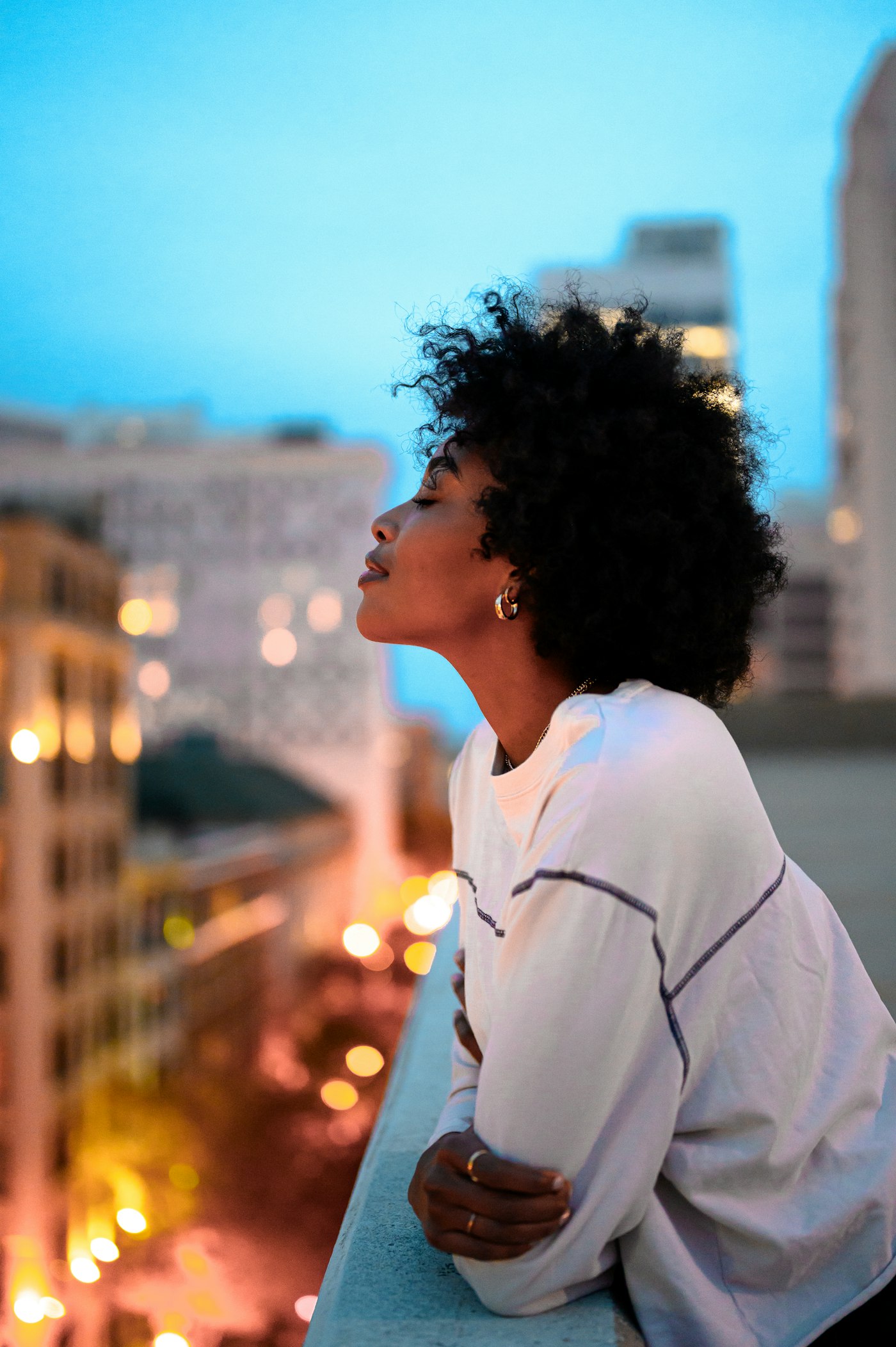 A young woman in a US city at dusk, looking out over the street